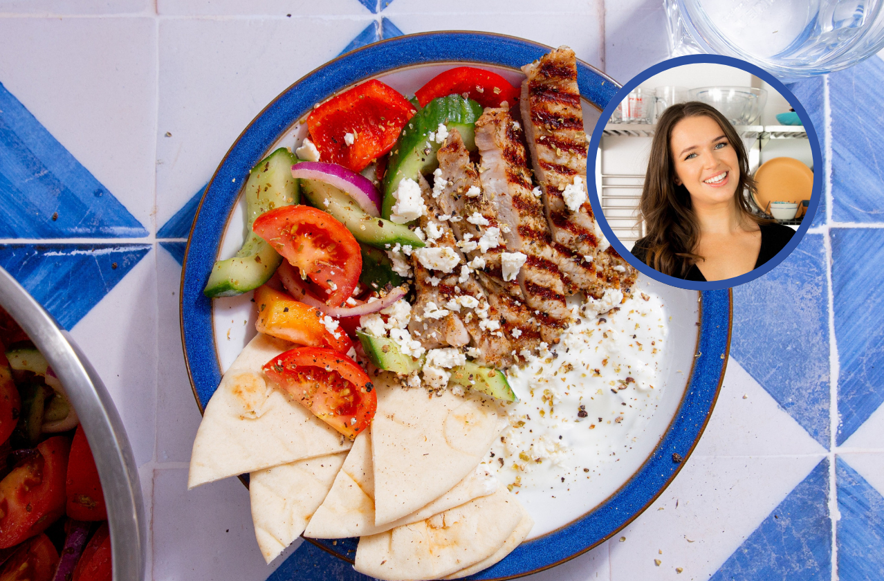 Pork gyros bowl with pork, pittas, salad and dip in a bowl on a blue and white tiled background