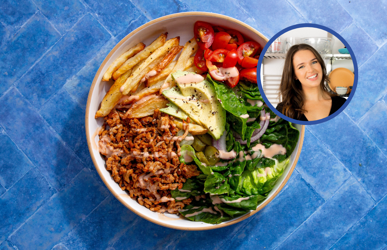 A deconstructed burger-style bowl with chips, pork mince, lettuce, avocado, and tomatoes. A woman's face is in the corner.