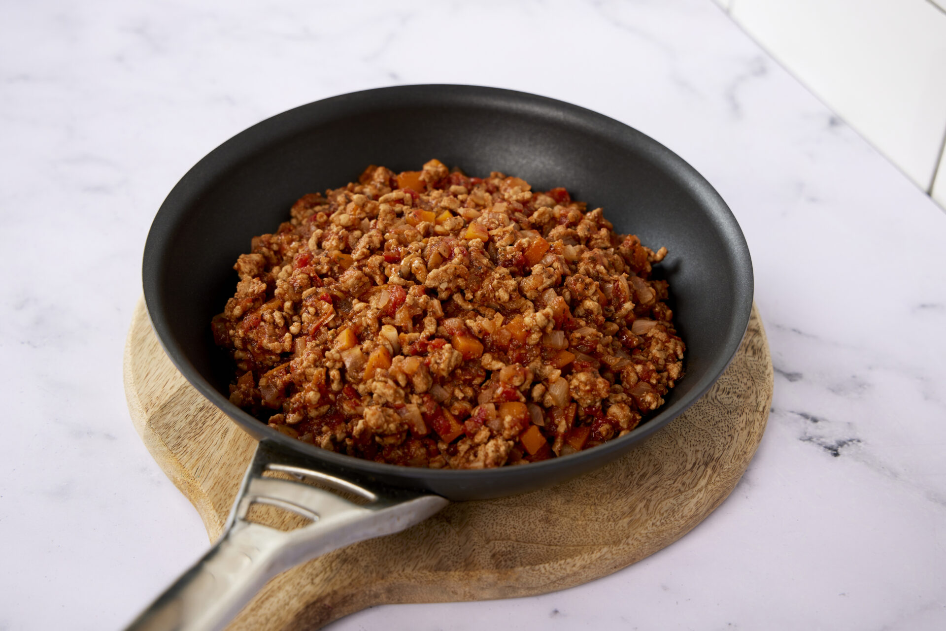 A large pan on a countertop, with cooked pork mince in it.