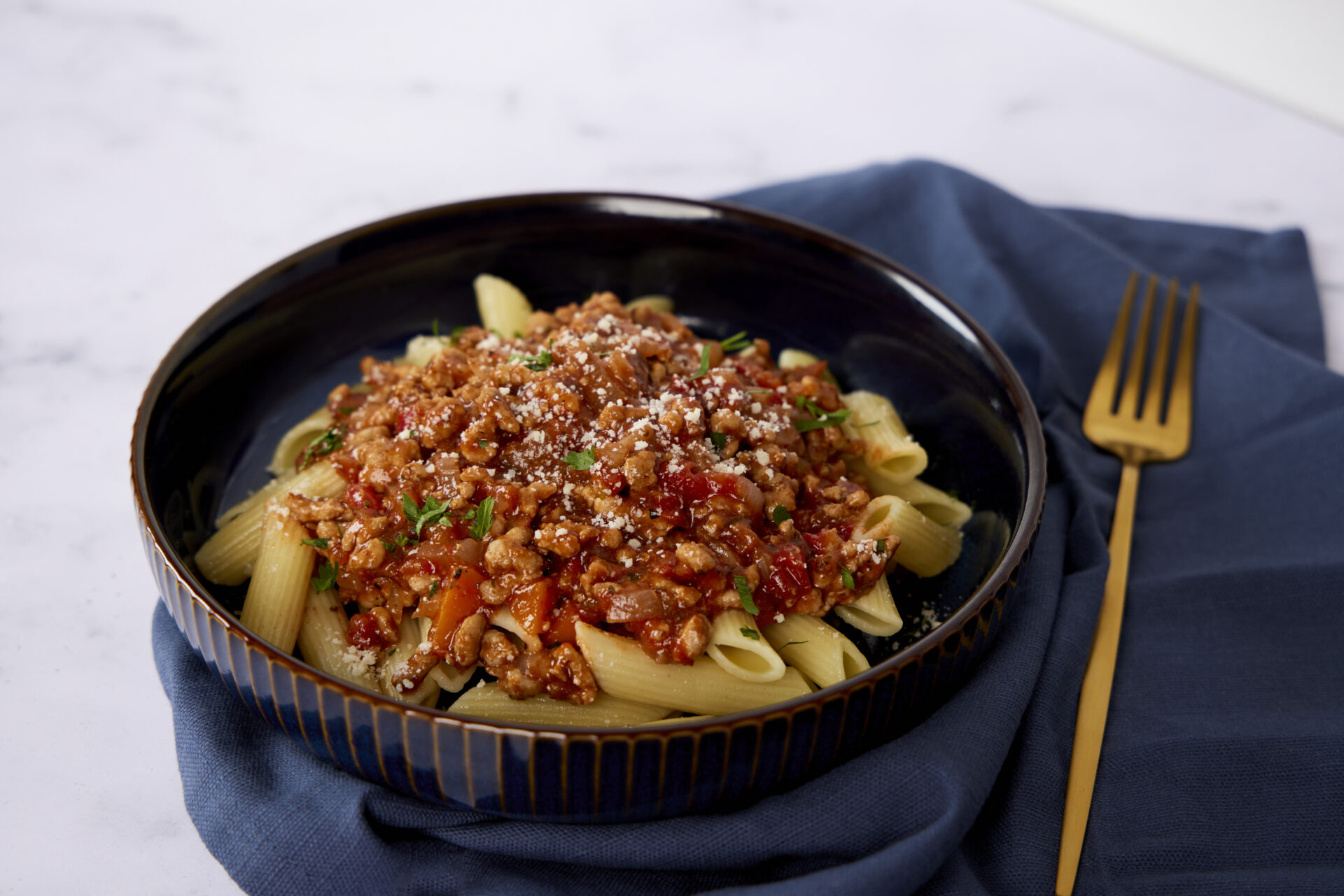 A bowl of pasta topped with a pork mince base and some cheese.