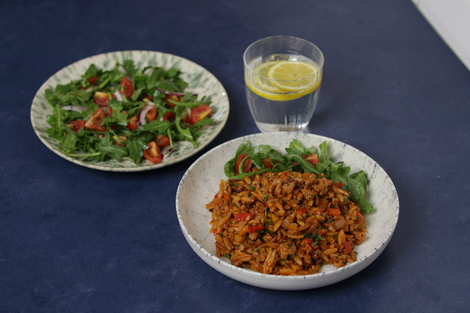 A dish containing pork and chipotle orzotto, with greens on the side.