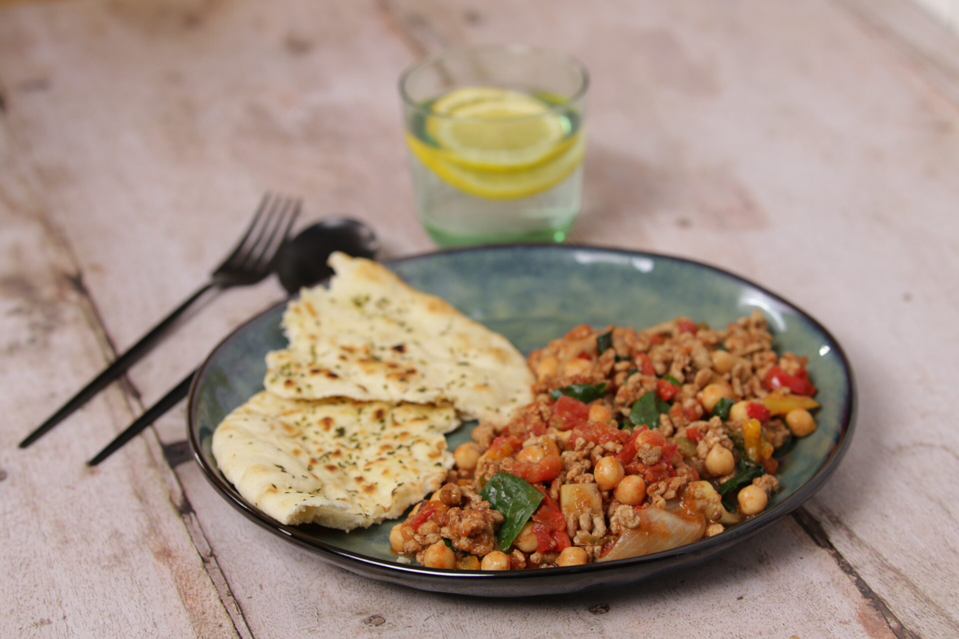 A dish containing a mix of pork mince and chickpeas, with flatbread on the side.