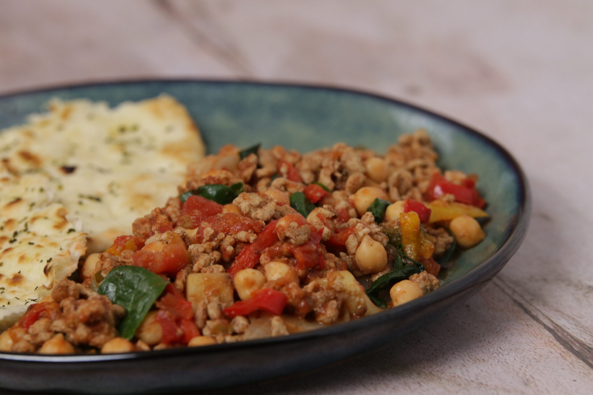 A dish containing a mix of pork mince and chickpeas, with flatbread on the side.
