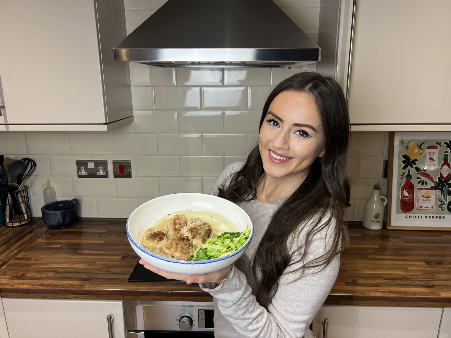 Rebecca Archer holding a plate of juicy pork and apple meatballs with mash in her kitchen
